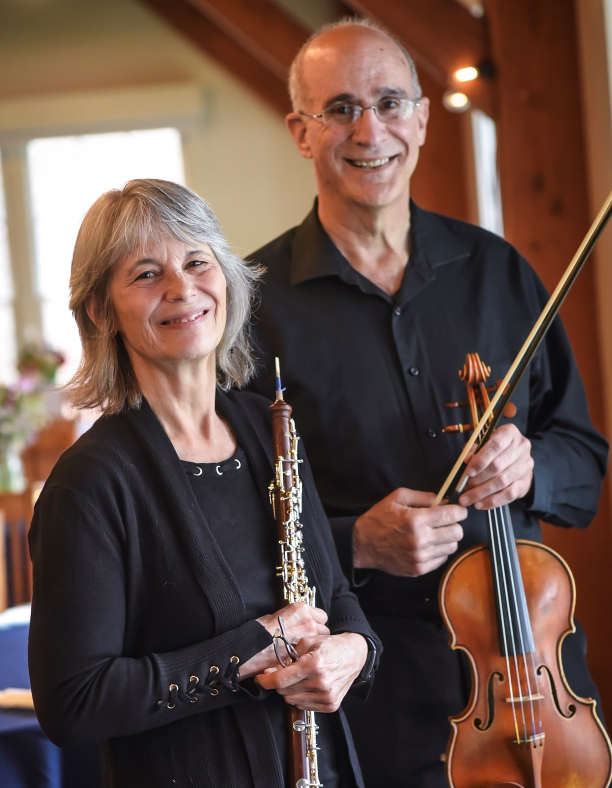 a white woman holding an oboe and a white man holding a violin